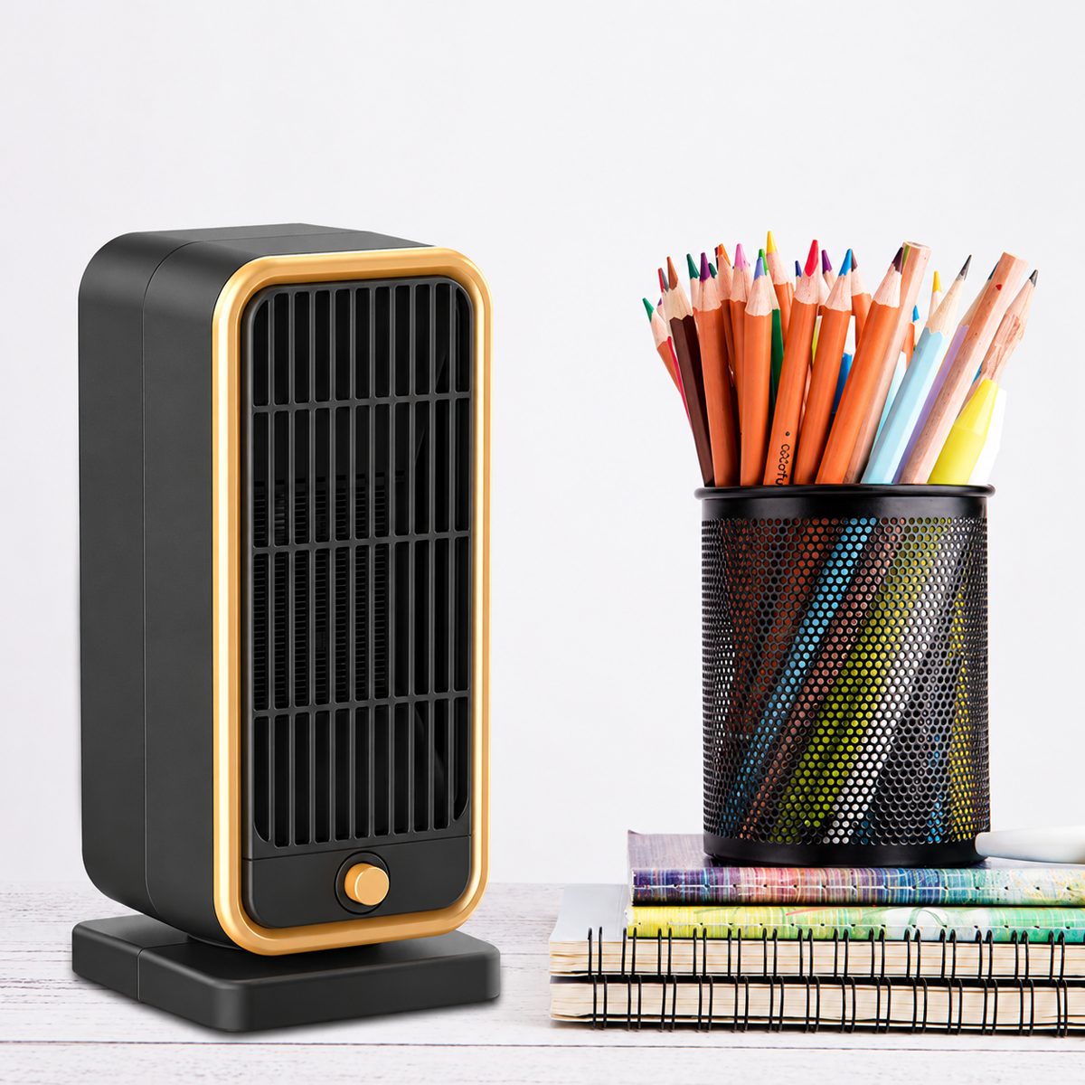 Keilini Heater Pro, a compact black tower heater with gold trim, on a desk beside a pencil pot
